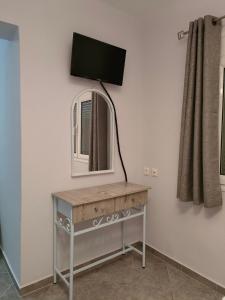 a mirror on a table with a tv on a wall at Pefki Apartment 9 in Artemísion +6 photos