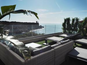 un patio con mesas y sillas y vistas al océano. en Hotel Rocamar, en Cala Figuera
