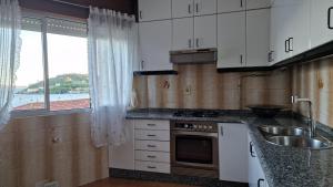 uma cozinha com armários brancos, um lavatório e uma janela em Apartamento Vistas Olas del Mar & Playa Raxó em Raxó