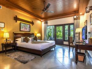 1 dormitorio con 1 cama grande y piano en Aahana The Corbett Wilderness, en Rāmnagar