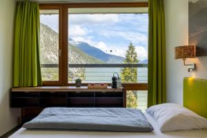 een slaapkamer met een groot raam met uitzicht op de bergen bij MyTirol in Biberwier