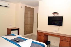 una camera con letto e TV a parete di Airport Hotel Peebles a Nuova Delhi
