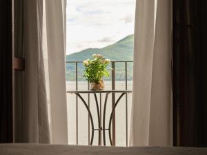 una mesa con un jarrón de flores en el balcón en Hotel Sole en Cannero Riviera