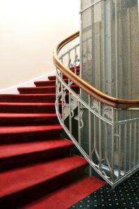 a staircase with red carpet and a metal railing at Hotel Fürst Bismarck in Hamburg