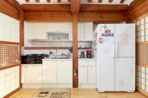 a kitchen with white cabinets and a refrigerator at Inwoo Guesthouse in Seoul