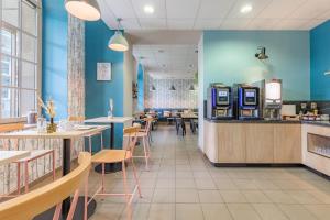 un restaurante con paredes azules, mesas y sillas en Appart’City Confort Reims Centre, en Reims