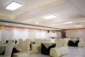 un salón de banquetes con mesas y sillas blancas en Hotel LA PEARL, Bhopal, en Bhopal