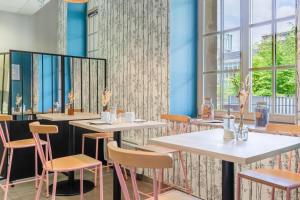 un restaurant avec des tables blanches, des chaises et des fenêtres dans l'établissement Appart’City Confort Reims Centre, à Reims
