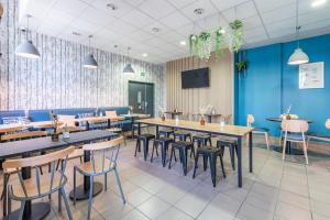 a restaurant with tables and chairs and a blue wall at Appart’City Confort Reims Centre in Reims +31 photos