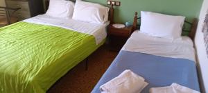two beds in a room with green and white sheets at Hotel zakros rooms-restaurant in Zákros