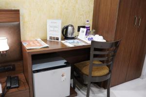 biurko z krzesłem obok małej lodówki w obiekcie Hotel LA PEARL, Bhopal w mieście Bhopal