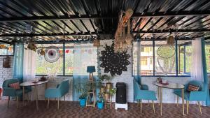 Habitación con 2 mesas, sillas y ventanas en Peace Inn Hostel & Kasolview Homestay en Kasol