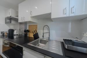 a kitchen with a stainless steel sink and white cabinets at Eiffel Playcation in Paris