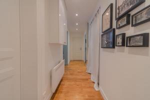 a hallway with white walls and wood floors and pictures on the walls at Eiffel Playcation in Paris