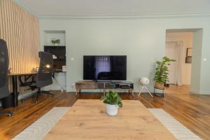a living room with a flat screen tv and a table at Eiffel Playcation in Paris
