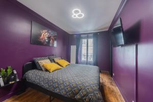 a bedroom with purple walls and a bed with yellow pillows at Eiffel Playcation in Paris