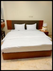 um quarto com uma cama grande e lençóis brancos em Museum comfort view Giza ' pyramids em Giza