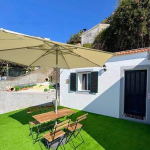 a patio with a table and chairs and an umbrella at Casa D'Avó Filó in Funchal