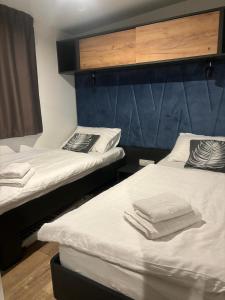 2 camas en una habitación con sábanas blancas y toallas en Olive Mobile Home, Terra Park SpiritoS, en Kolan