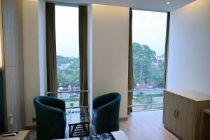 Zimmer mit 2 Stühlen und großen Fenstern in der Unterkunft HOTEL CASA ROYALE in Amritsar