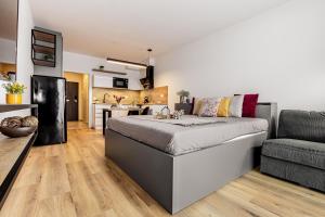 a bedroom with a bed and a couch and a kitchen at KORZO Couple in Lipno nad Vltavou