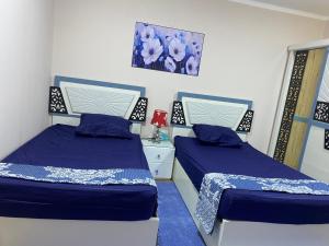 duas camas num quarto com azul e branco em Cozy Nile view apartment em Asyut