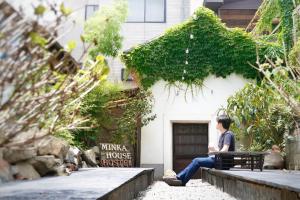 een man op een bankje voor een huis bij Minka House in Matsumoto