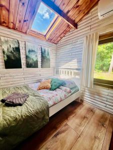Urocza chatka w lesie nad wodą في Skubianka: غرفة نوم مع سرير في غرفة مع نافذة