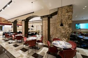 un restaurante con mesas y sillas y una pared de piedra en Catalonia Plaza Catalunya, en Barcelona