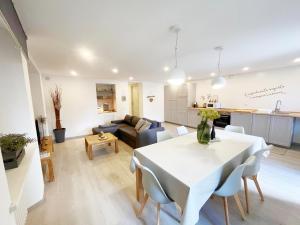soggiorno e cucina con tavolo e sedie bianchi di Insieme nel cuore di Aosta - You & Me case Vacanza ad Aosta