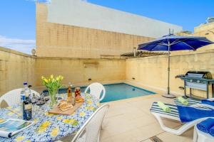 a patio with a table and a swimming pool at Ta'Sandrija Pool And Well-Being In Gozo - Happy Rentals in Taʼ Bullara