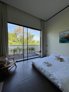 a bedroom with a large bed and a large window at Cosmo Villa by Labala in Ban Klang Na