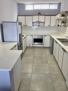 an empty kitchen with white cabinets and appliances at Beach front, two story condo in Ballito +7 photos
