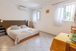 a white bedroom with a bed and a table at Apartments Baričević in Bol