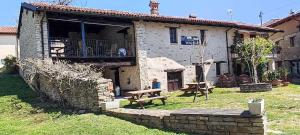 a stone house with a picnic table and a bench at Ca' Pavaglione Country House in Borgomale