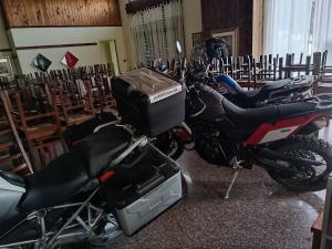 twee motorfietsen geparkeerd in een kamer met rijen stoelen bij bed and breakfast Murales Orgosolo in Orgosolo