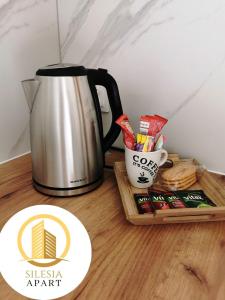 a table with a coffee pot and a tray of snacks at Apartament Miedziany in Tychy