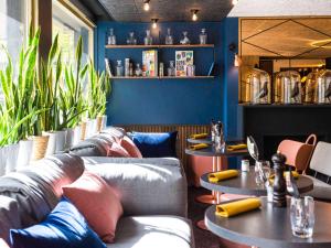 una habitación con sofás y mesas en un restaurante en Mercure Bordeaux Centre Ville, en Burdeos