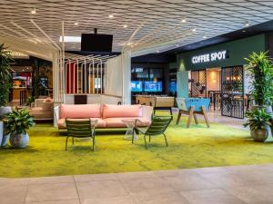 een lobby met een bank en stoelen in een winkel bij ibis Paris CDG Airport in Roissy-en-France