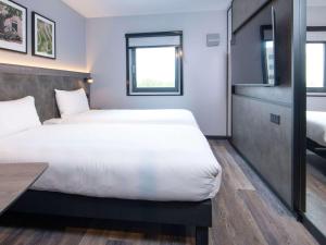 Cette chambre comprend 2 lits et une table. dans l'établissement ibis Styles London Gatwick Airport, à Crawley