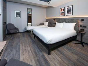 a hotel room with two beds and a chair at ibis Styles London Gatwick Airport in Crawley