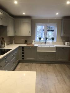 eine Küche mit weißen Schränken und einer Spüle und einem Fenster in der Unterkunft Orchard Cottage in Lincolnshire