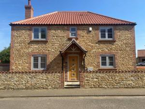 ein Backsteinhaus mit einem roten Dach und einer gelben Tür in der Unterkunft Orchard Cottage in Lincolnshire
