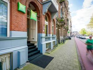 a woman walking down a street in front of buildings at ibis Styles Amsterdam City in Amsterdam