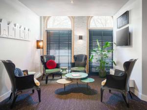 een wachtkamer met stoelen, een tafel en een raam bij ibis Styles Amsterdam City in Amsterdam