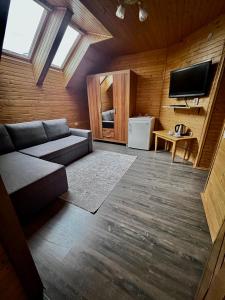 ein Wohnzimmer mit einem Sofa und einem Flachbild-TV in der Unterkunft Боброва-Хата in Switjas