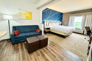 une chambre d'hôtel avec un lit et un canapé bleu dans l'établissement Comfort Suites East Brunswick - South River, à East Brunswick