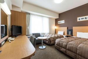 a hotel room with two beds and a desk at Comfort Hotel Naha Prefectural Office in Naha