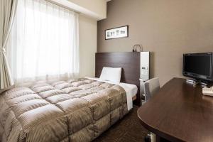 Habitación de hotel con cama grande y escritorio. en Comfort Hotel Naha Prefectural Office, en Naha