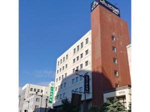 un grand bâtiment en briques avec un panneau en haut dans l'établissement HOTEL TETORA ASAHIKAWA EKIMAE - Vacation STAY 91502v, à Asahikawa